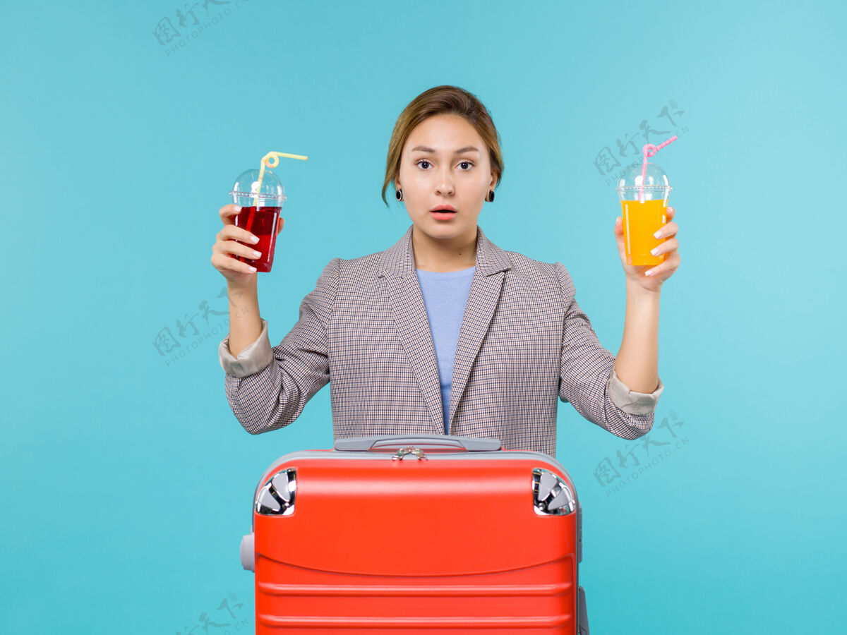 航行前视图：度假中的女性手持新鲜饮料乘坐蓝色背景的旅行旅行度假海上飞机女人前方工作