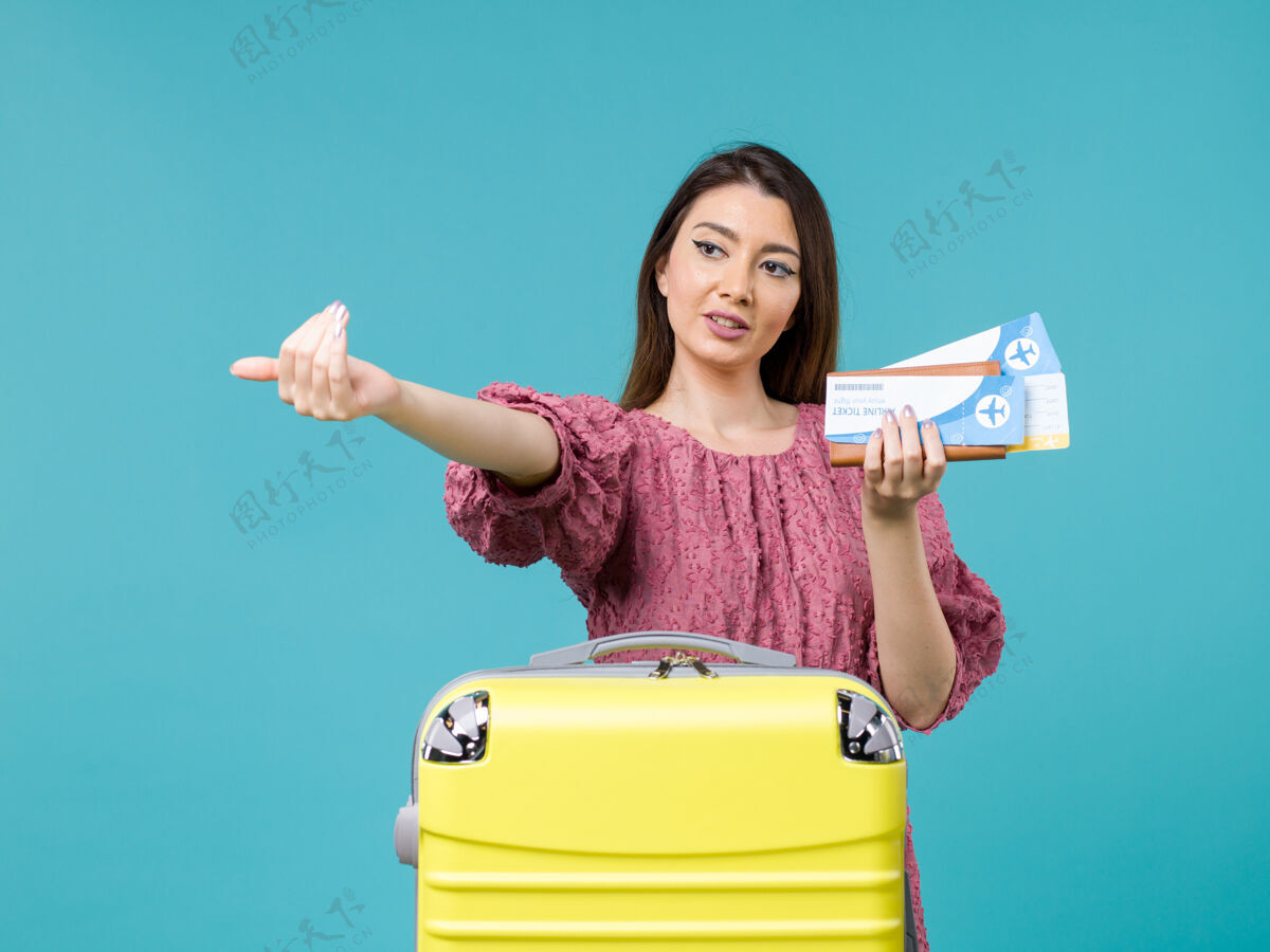 视图正面图：度假中的女性拿着钱包和蓝色背景上的机票旅行女性暑假海上旅行假期票女人