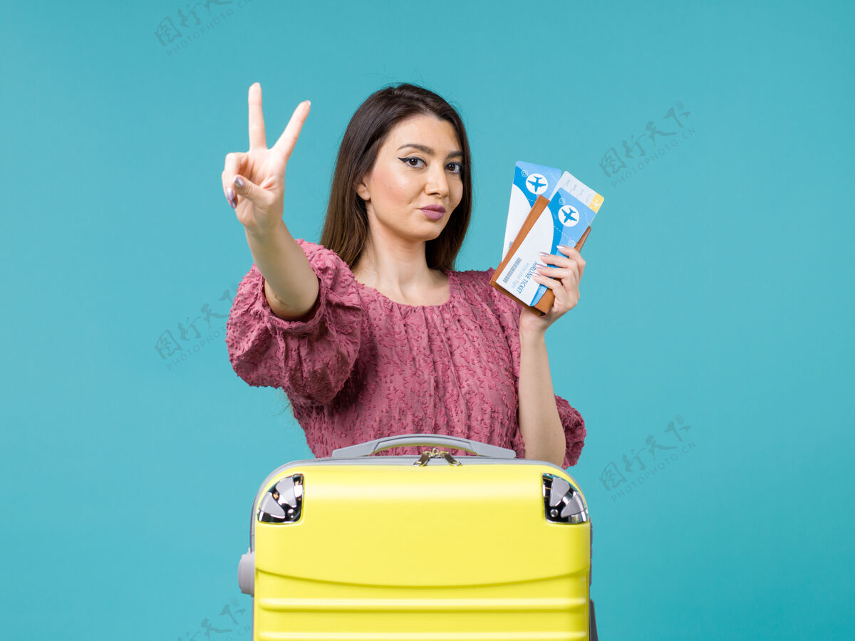 女人前景度假中的女人拿着蓝色背景的机票旅行暑期旅行的女人海人成人旅行蓝色