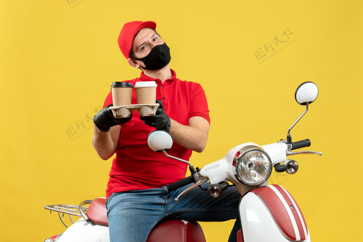 人俯视图微笑的送货员身穿制服 戴着帽子手套 戴着医用面罩 坐在滑板车上发号施令快乐运动摩托车