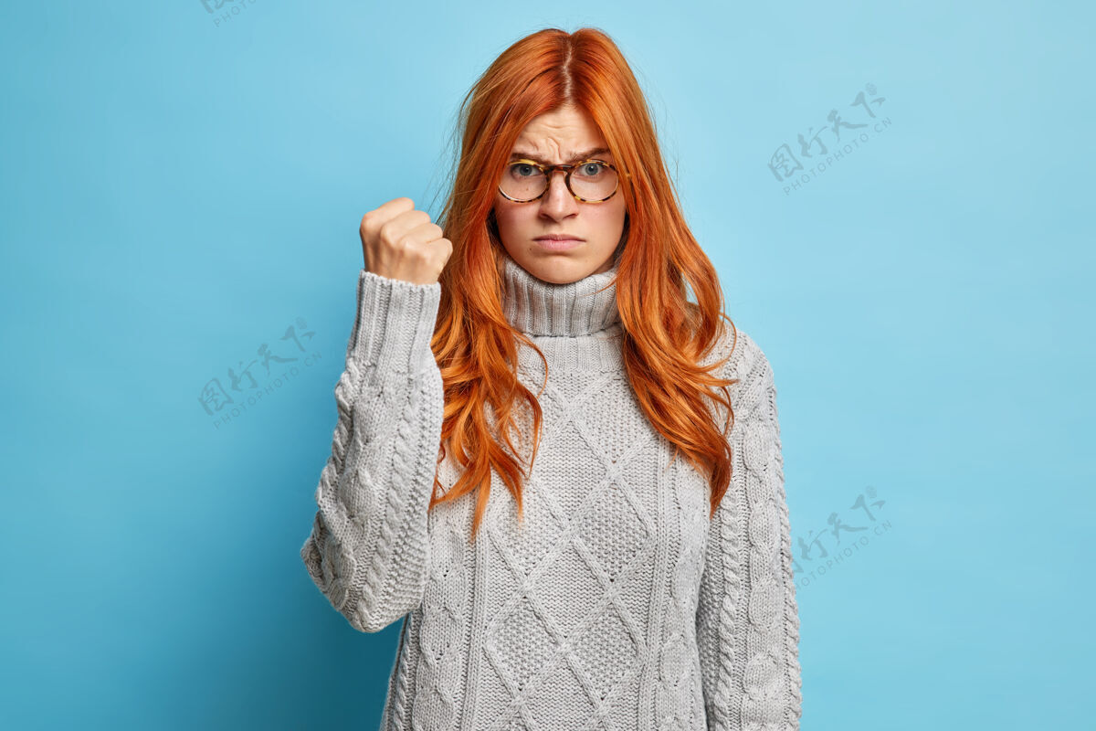 白种人年轻的红发女子穿着休闲针织毛衣 怒气冲冲地握紧拳头 表情不悦肖像美丽疯狂