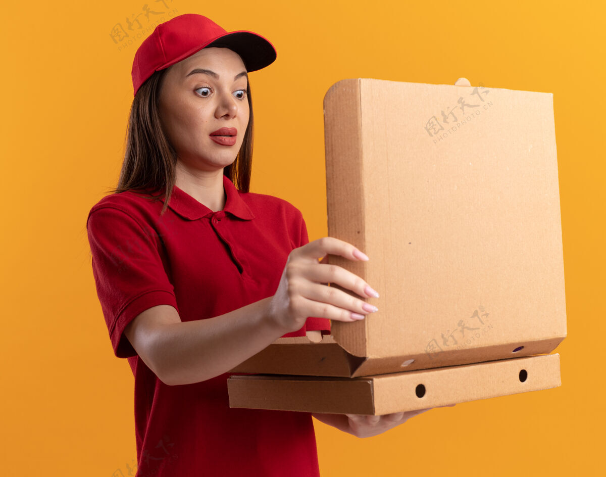 女人一个穿着制服的漂亮送货员拿着披萨盒看着橙色的披萨盒盒子披萨漂亮