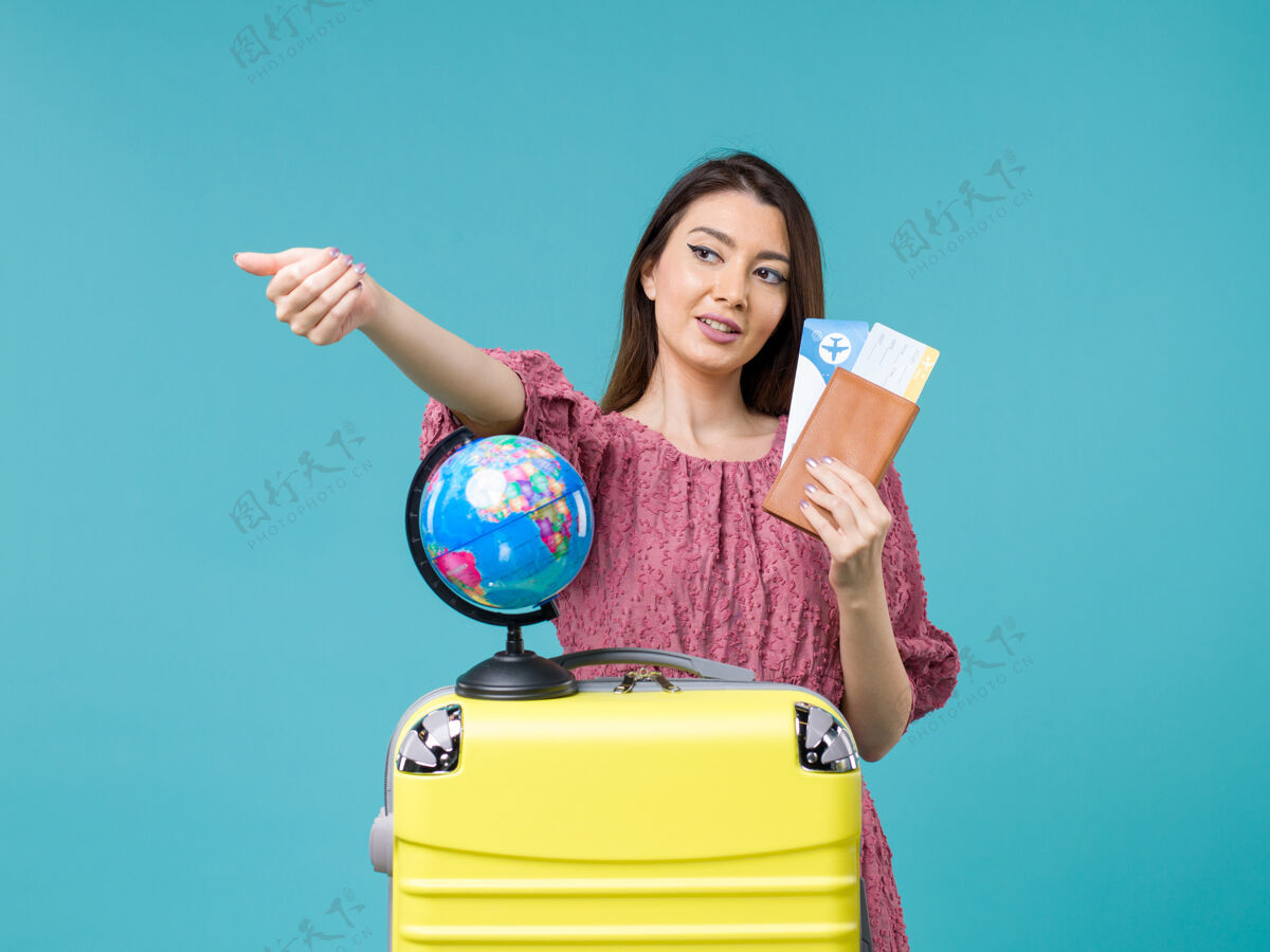 肖像前视图女性在旅行中拿着她的机票在蓝色背景海上旅行度假女性旅行女人前面蓝色