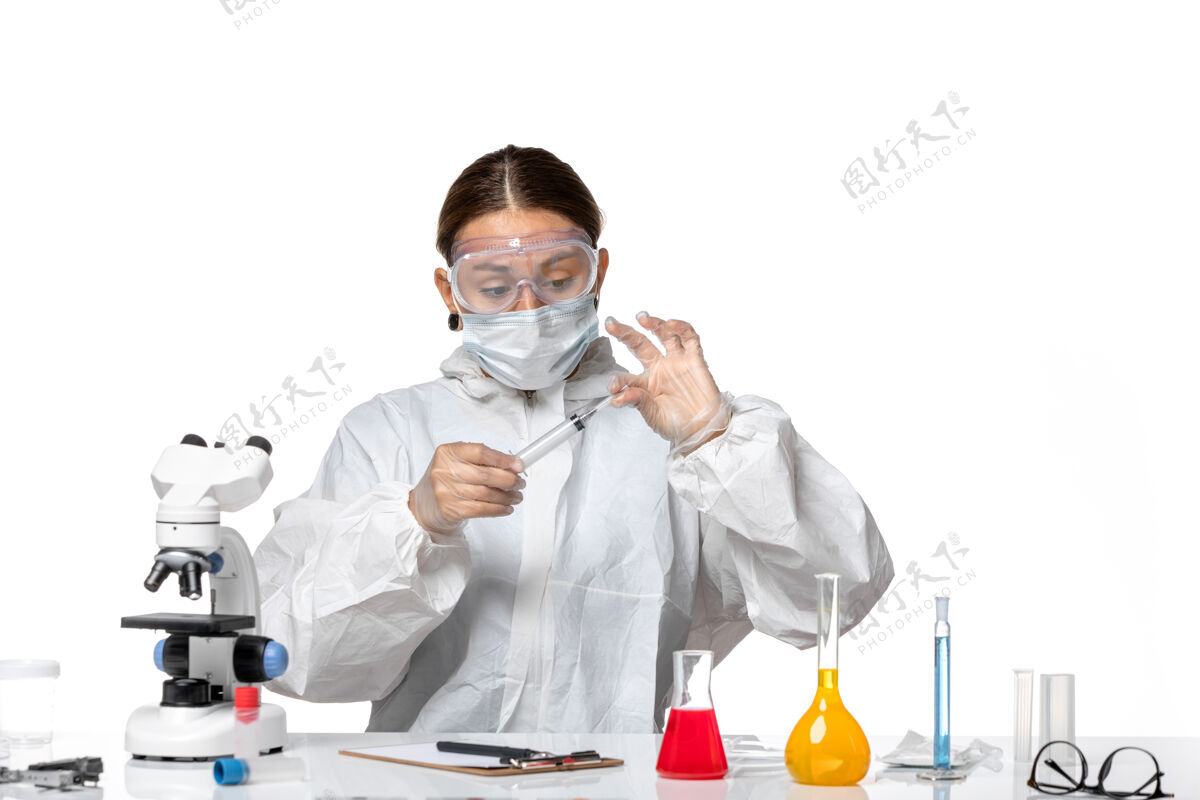 药品前视图穿着防护服 戴着口罩的女医生正在注射白色背景病毒药物covid大流行外套实验室外套专业