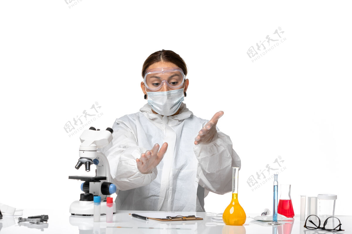 药品前视图：身着特殊套装 戴着口罩的女医生 背景为浅白色的冠状病毒大流行成人健康病毒