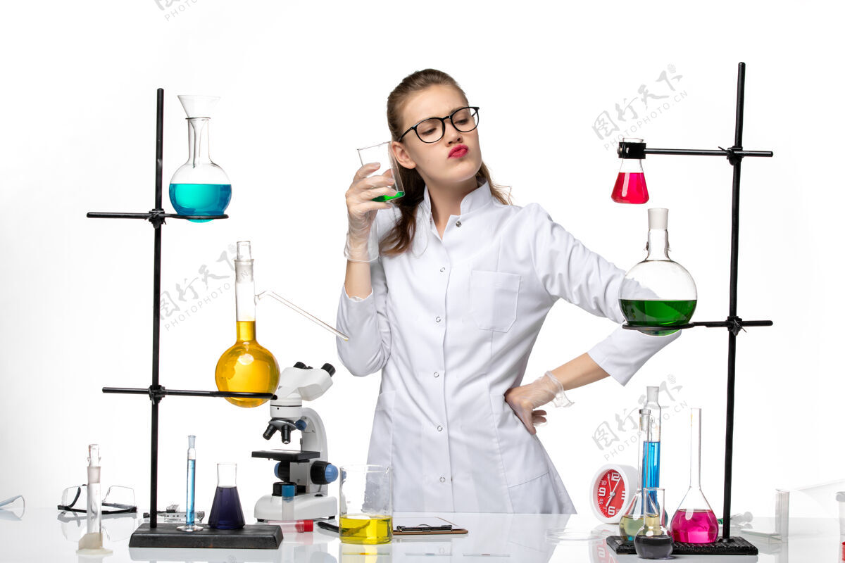 女化学家前视图身着医疗服的女化学家在工作过程中用浅白背景上的溶液化学大流行的病毒化学专业光