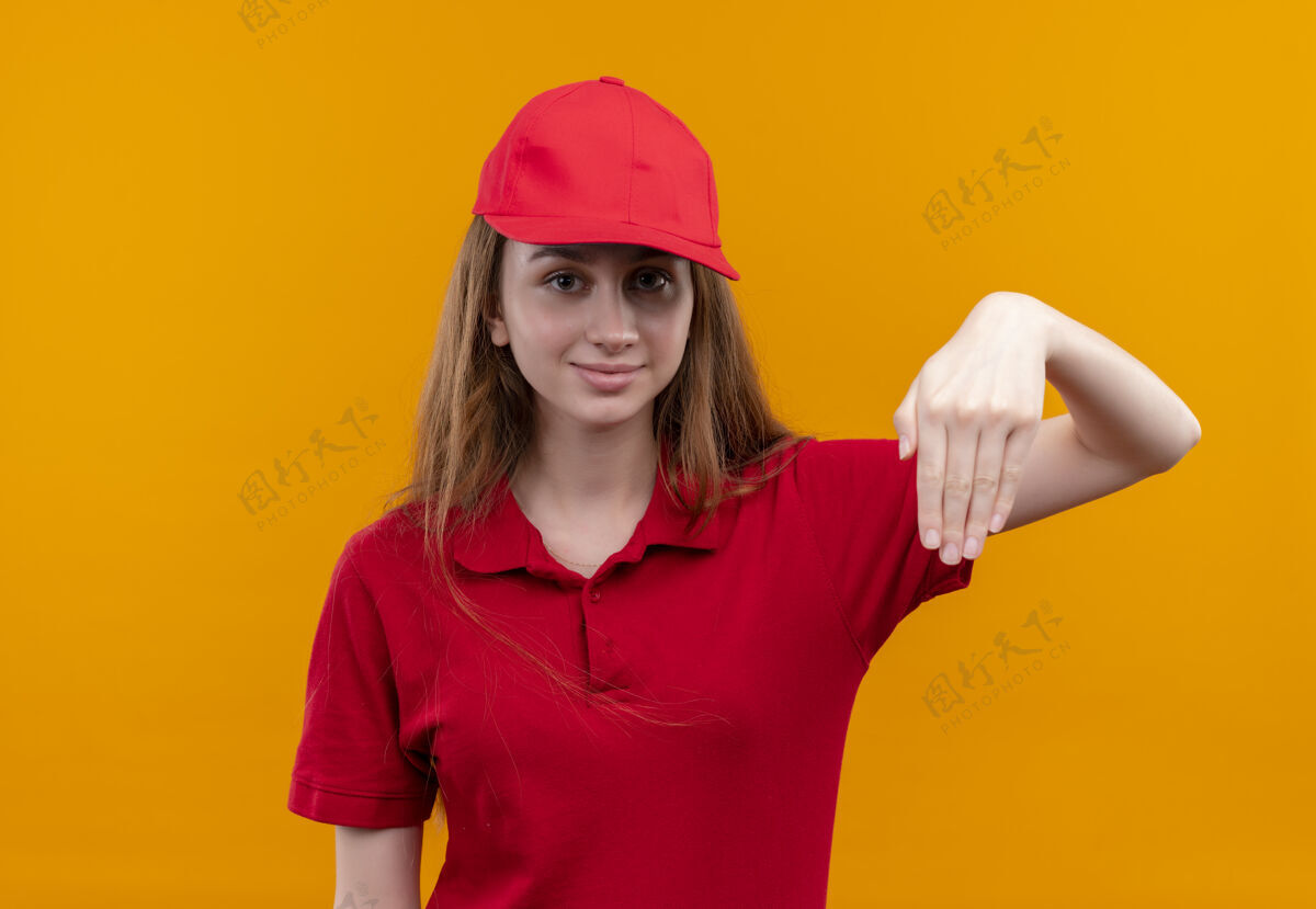 橙色自信的年轻送货女孩穿着红色制服 用手指着孤立的橙色空间向下红色信心