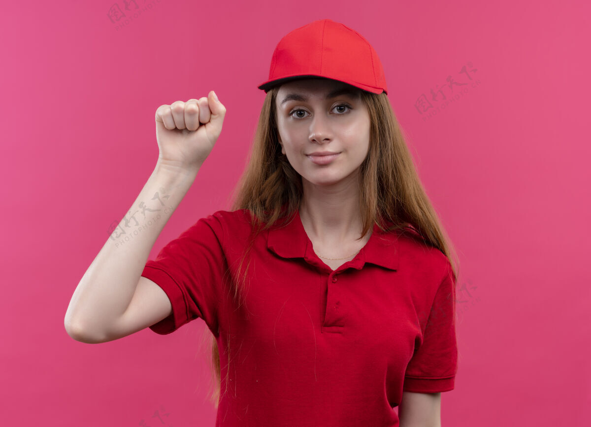 粉色穿着红色制服的自信的年轻送货女孩在孤立的粉色空间做敲门手势年轻制服自信