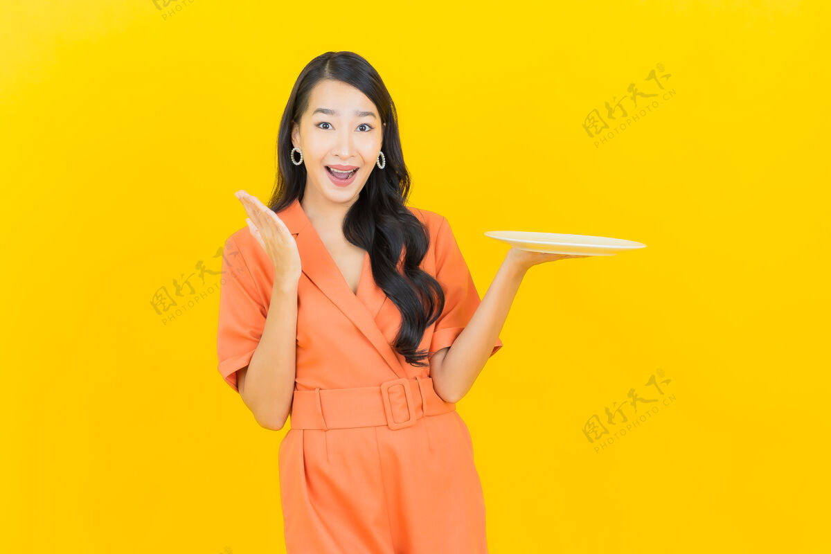 面包师肖像美丽的亚洲年轻女子微笑 黄色的空盘子给予食物烹饪