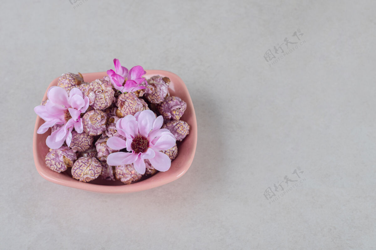 自然粉红色的碗里装满了用鲜花装饰的爆米花 放在大理石桌上垃圾食品小吃美味