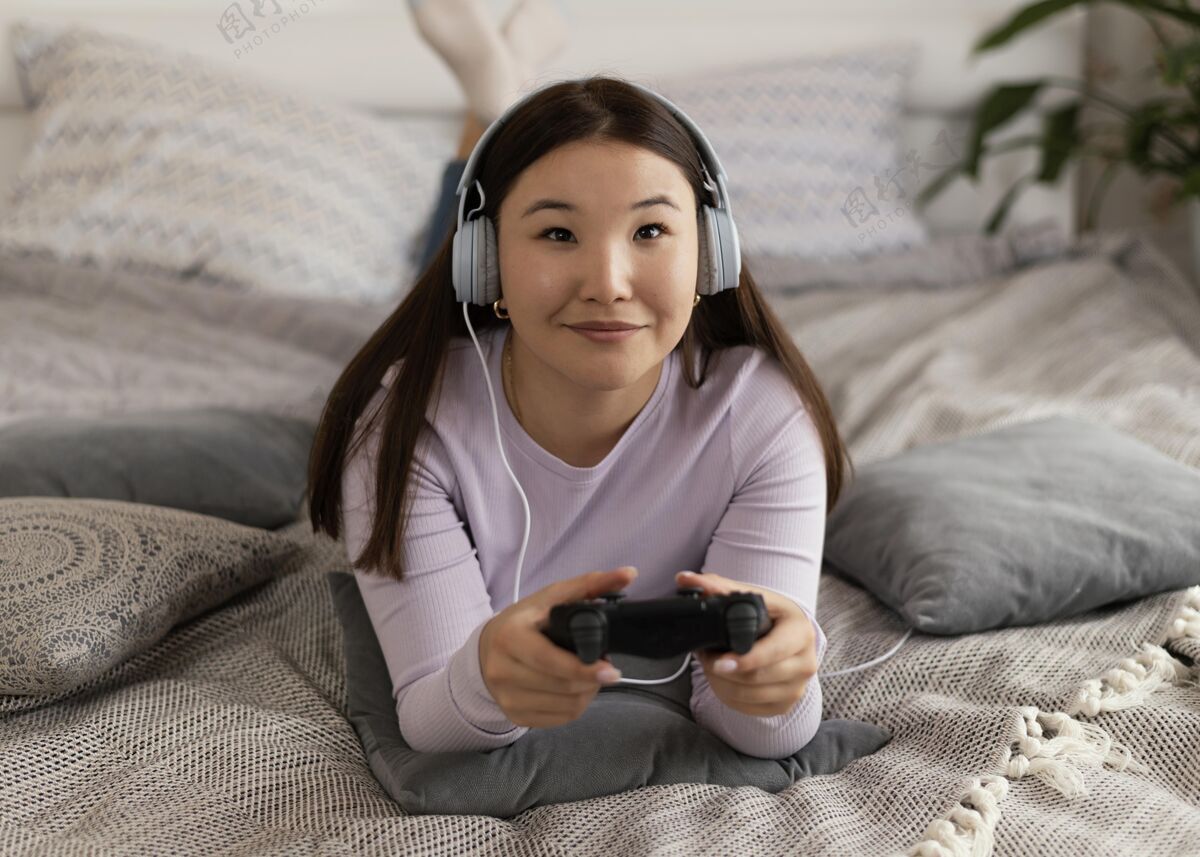 水平在床上玩电子游戏的女孩全拍玩家娱乐耳机