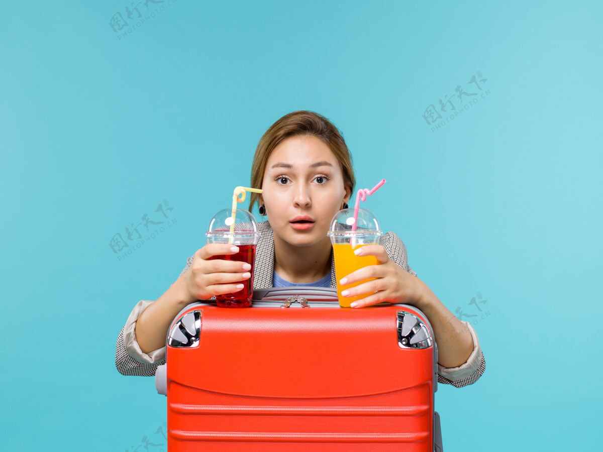 人前景度假中的女性手持淡蓝色背景的新鲜饮料旅行度假海上飞机举行度假区度假
