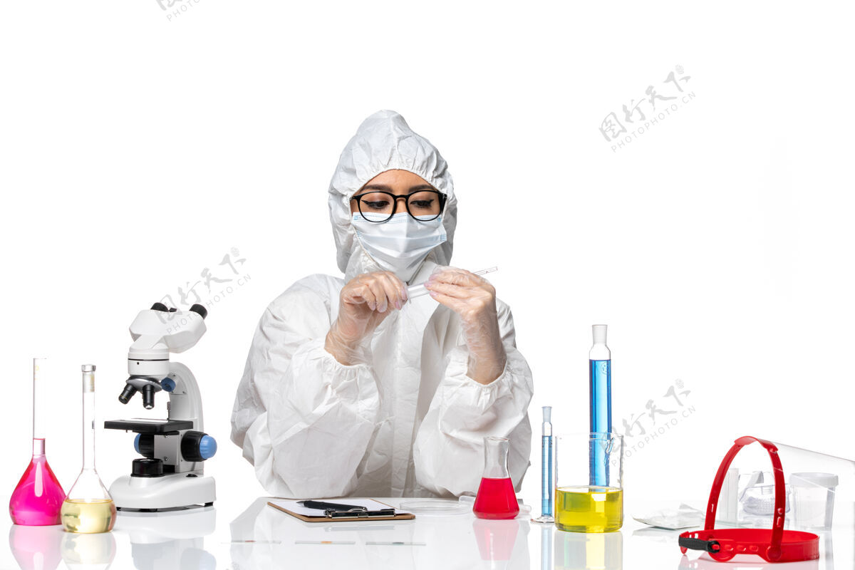 医学前视图穿着特殊防护服的女化学家坐在浅白背景上 解决化学冠状病毒大流行医学专业坐着