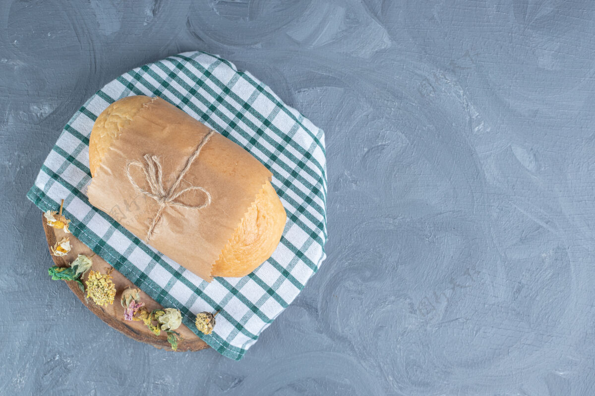 美味把面包包在大理石桌上用干花装饰的木板上面包房纸面包