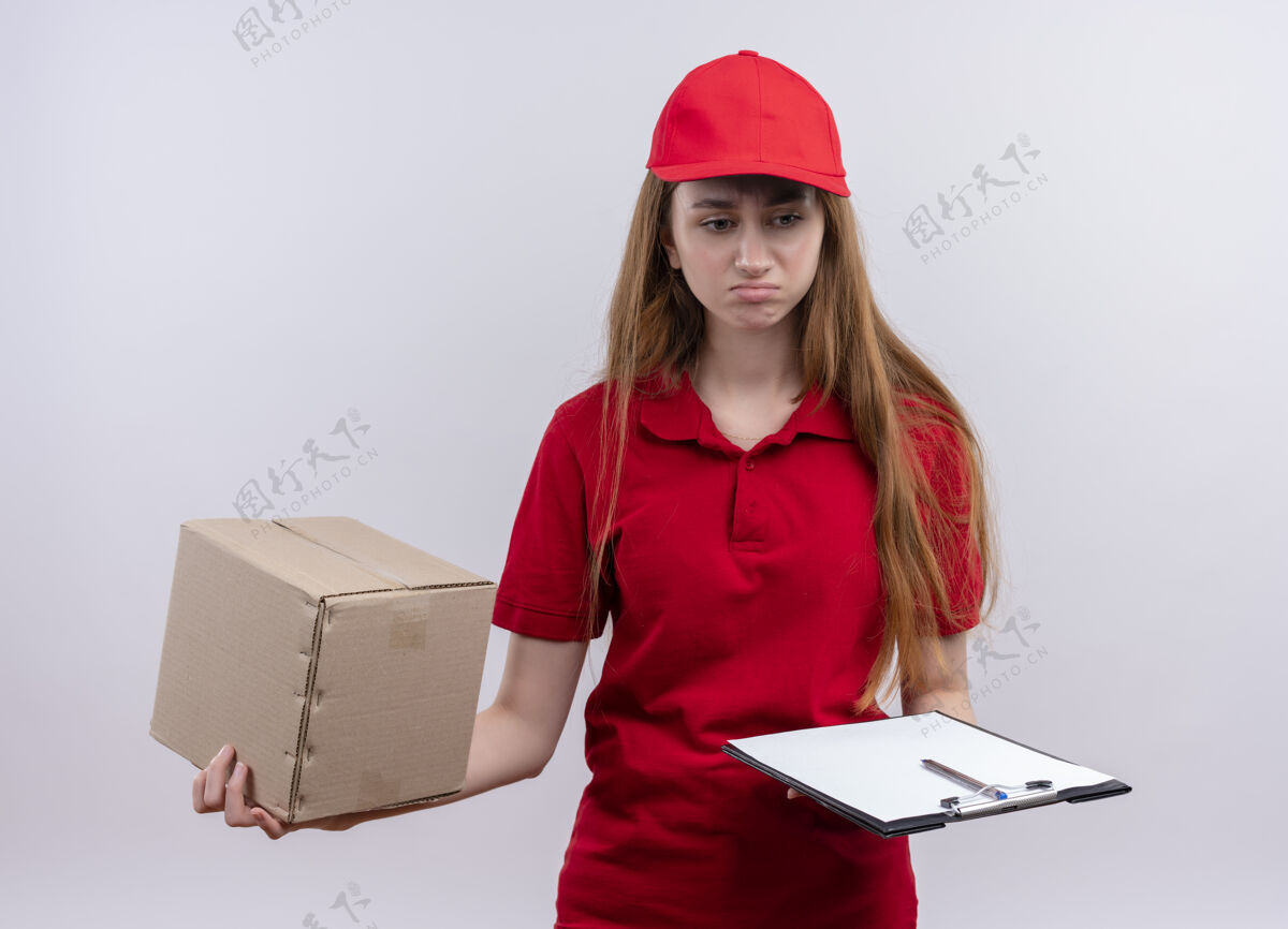 持有失望的年轻送货女孩在红色制服举行的盒子和剪贴板上孤立的白色空间制服失望红色