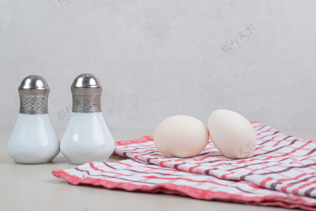 生的两个新鲜的鸡蛋放在桌布上鸡蛋盐生的