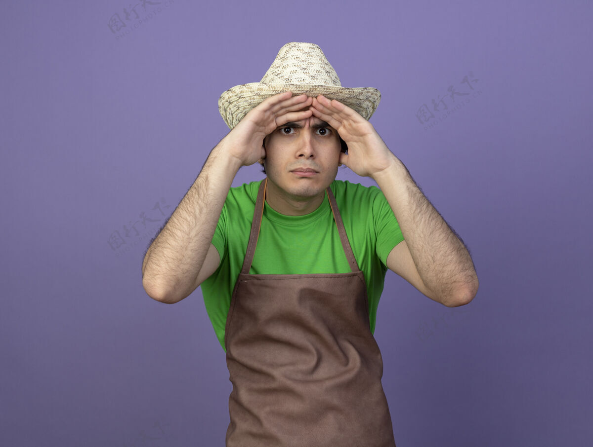 男人年轻的男园丁穿着制服戴着园艺帽用手看着远处园艺男人帽子