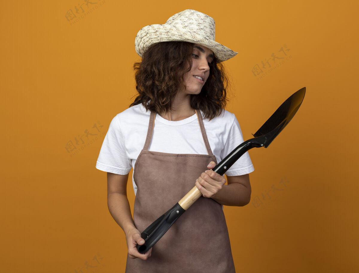 黑桃穿着制服的年轻女园丁戴着园艺帽 拿着铲子 看着铲子穿印象女人
