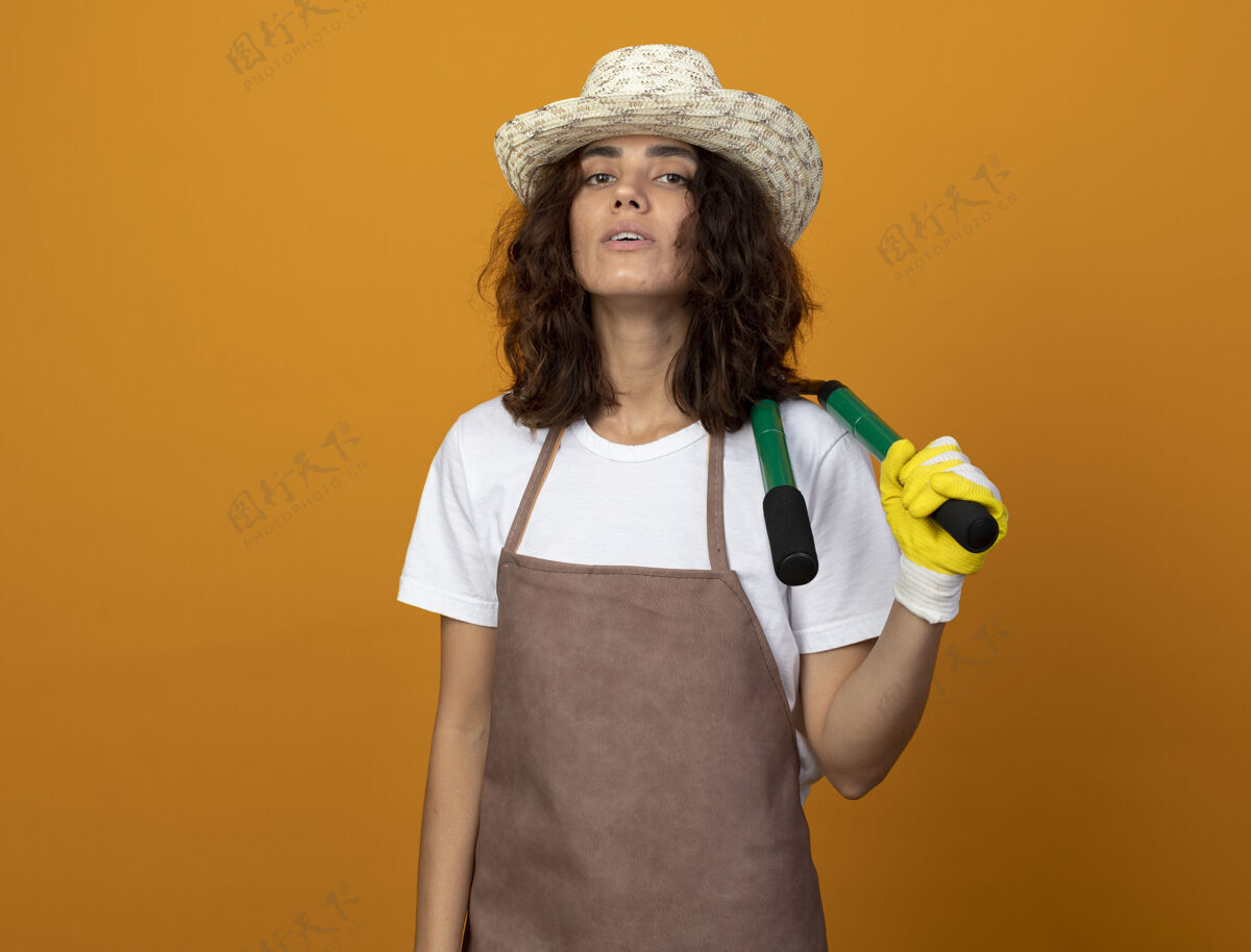 女人自信的年轻女园丁 穿着制服 戴着园艺帽和手套 肩上扛着铲子肩膀穿黑桃