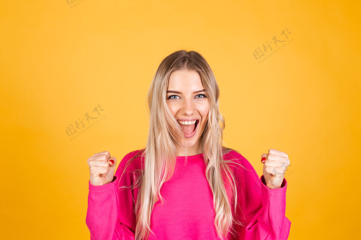 庆祝黄色墙上穿粉红色上衣的漂亮欧洲女人是聪明随意