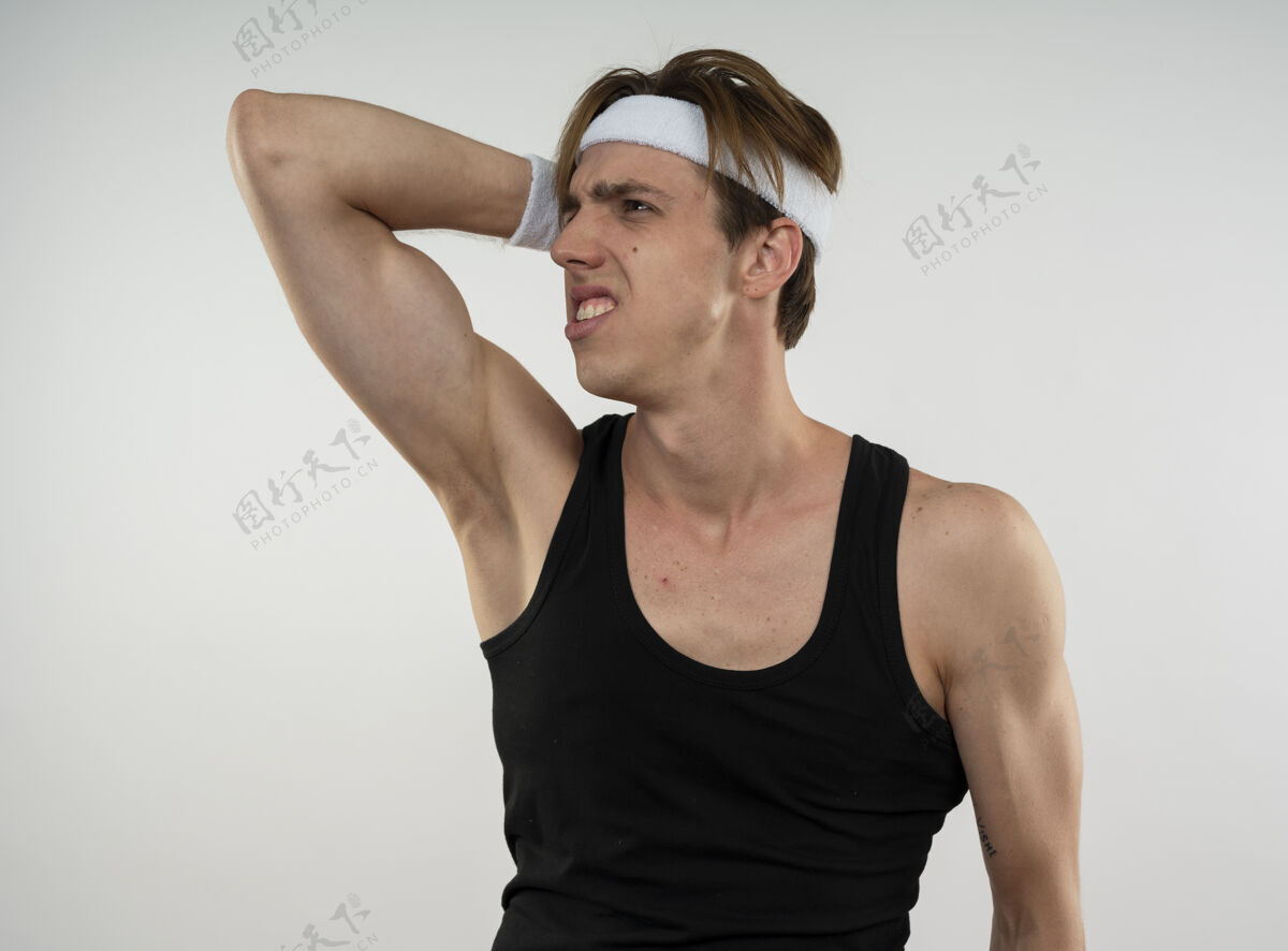 运动遗憾的是 年轻的运动型男人一边看一边戴着头带和腕带 一边把手放在头上 隔离在白墙上壁板后悔腕带