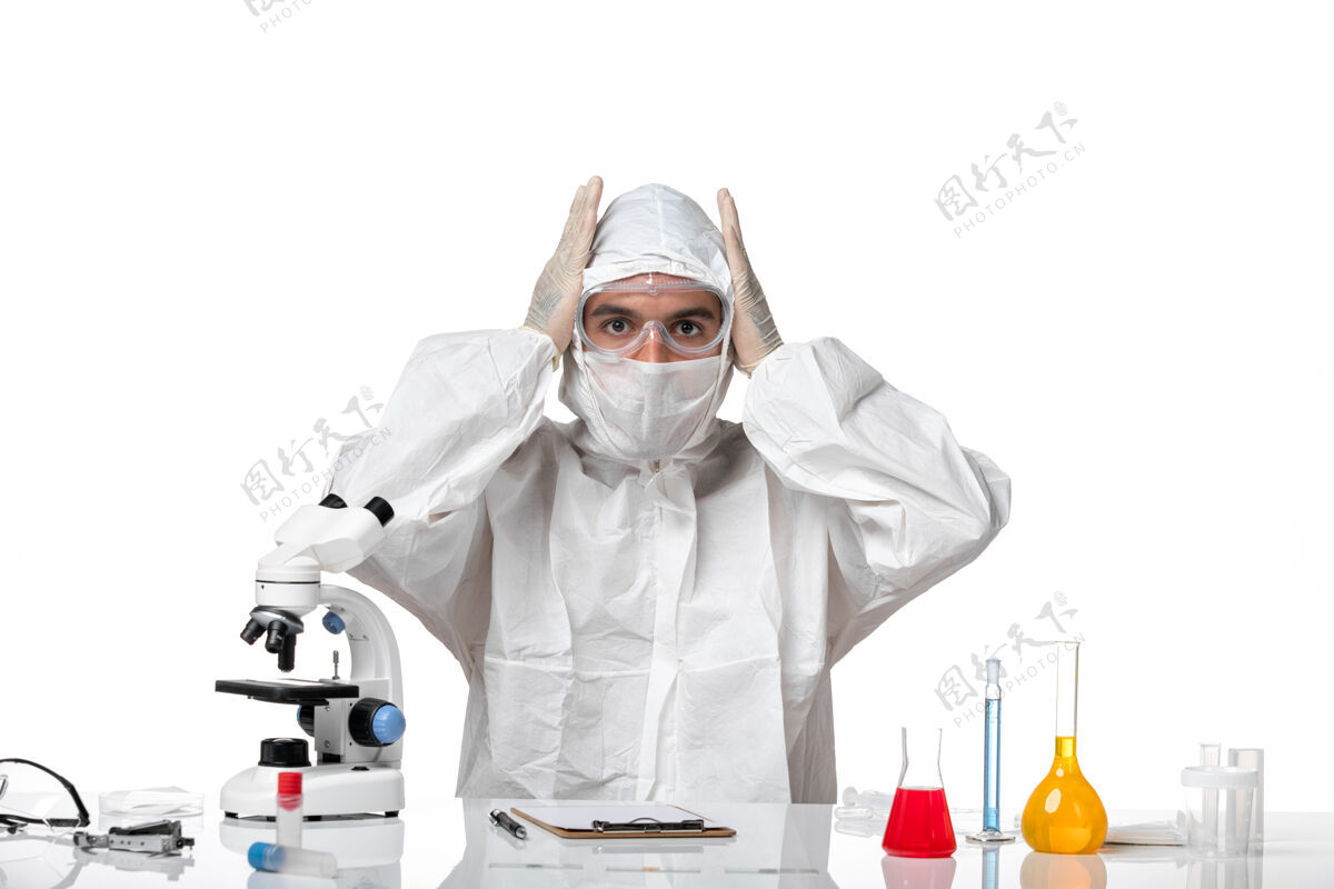 健康正面图：男医生穿着防护服 戴着面具 因为科维德坐在白色空间里摆姿势姿势套装人