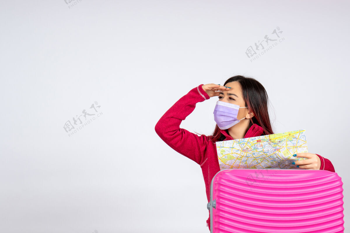 颜色正面图年轻女性戴着粉红色的面具在白色的墙上度假大流行病毒冠状病毒彩色旅行的女人游客病毒美女