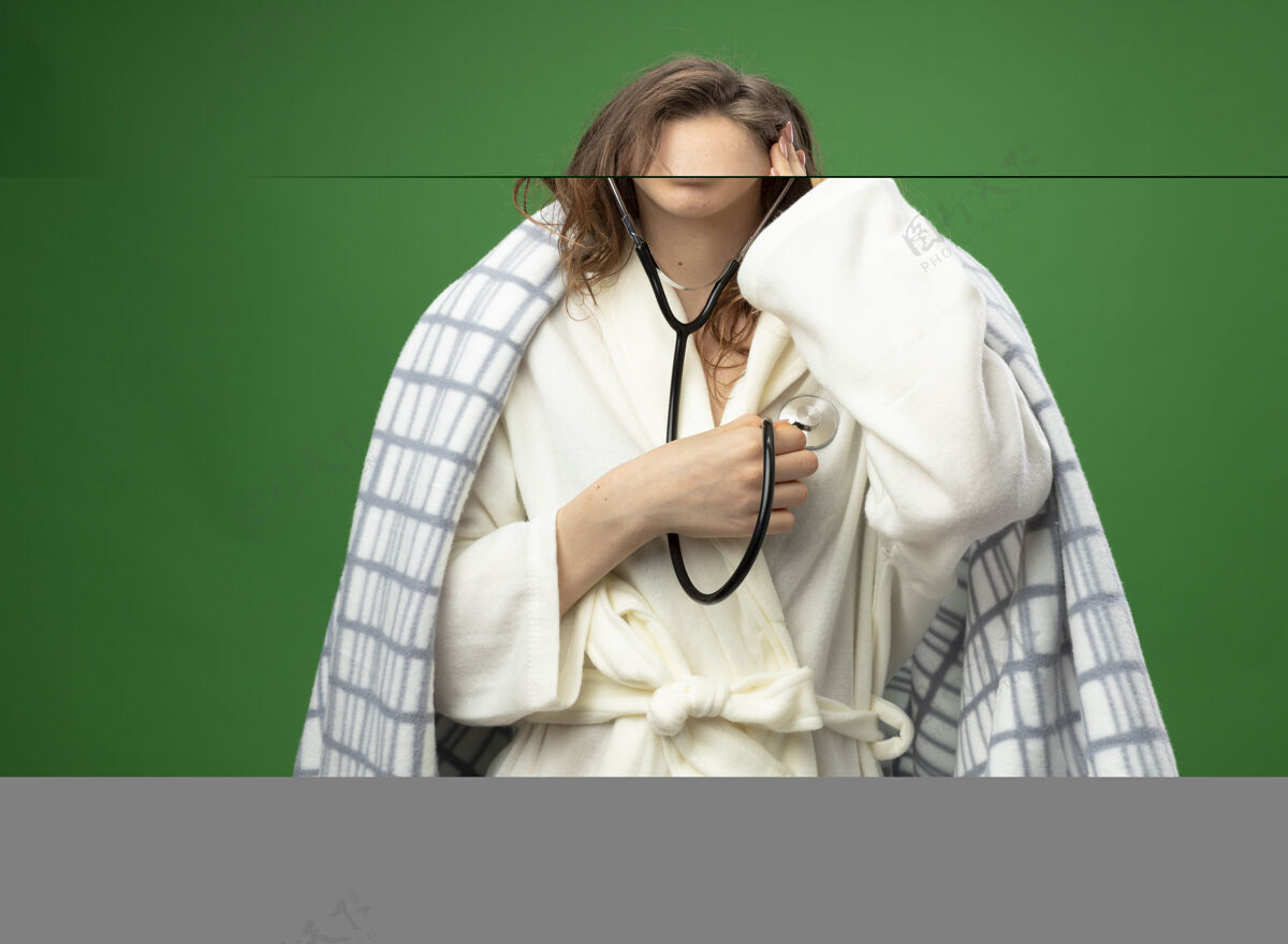 听诊器被吓坏了的年轻病女孩穿着格子布裹着的白色长袍 用听诊器把手放在头上 听自己的心跳长袍绿色害怕