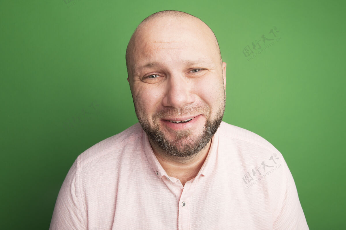 人愁眉苦脸直视前方的中年秃头男子身穿粉色t恤隔离在绿色随便女人