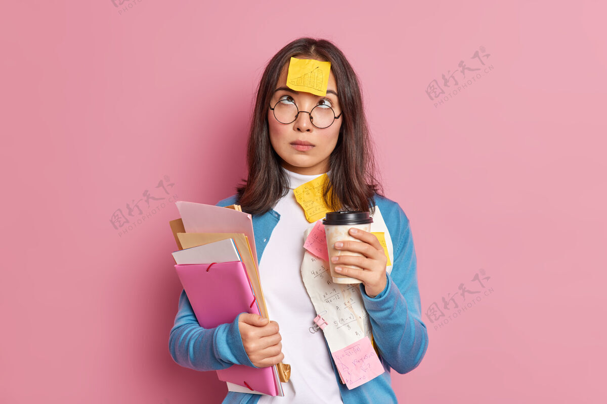 女性严肃女学生的照片有咖啡休息时间集中在上面有提醒贴贴在额头上贴纸姿势沮丧