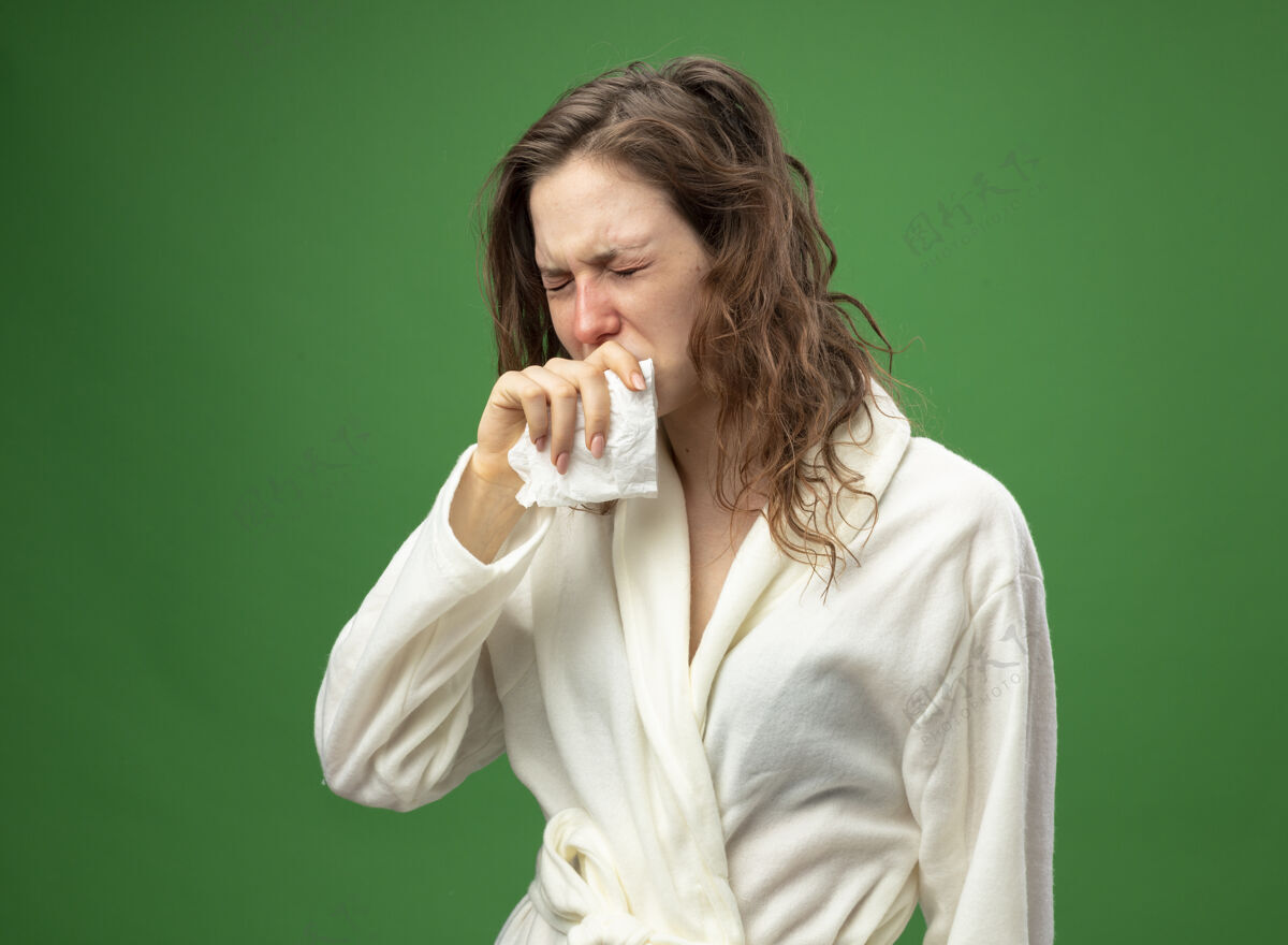 咳嗽虚弱咳嗽的年轻病女孩穿着白色长袍拿着餐巾把手放在嘴上隔离在绿色抱袍幼
