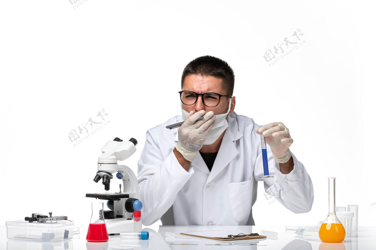 医生正面图：男医生穿着白色医疗服 戴着面罩 在一个空白处用溶液工作工作男性医生溶液