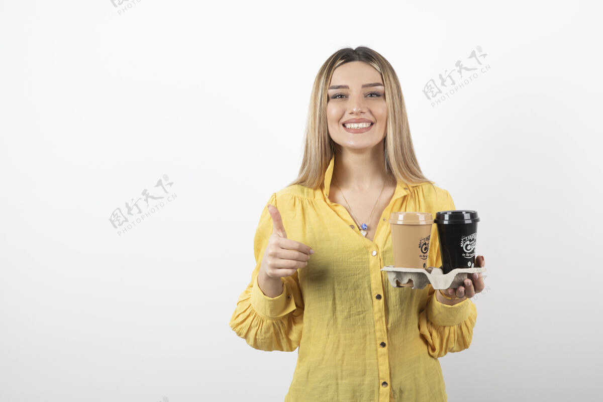 咖啡年轻女子拿着咖啡 竖起大拇指的肖像盖子人女人