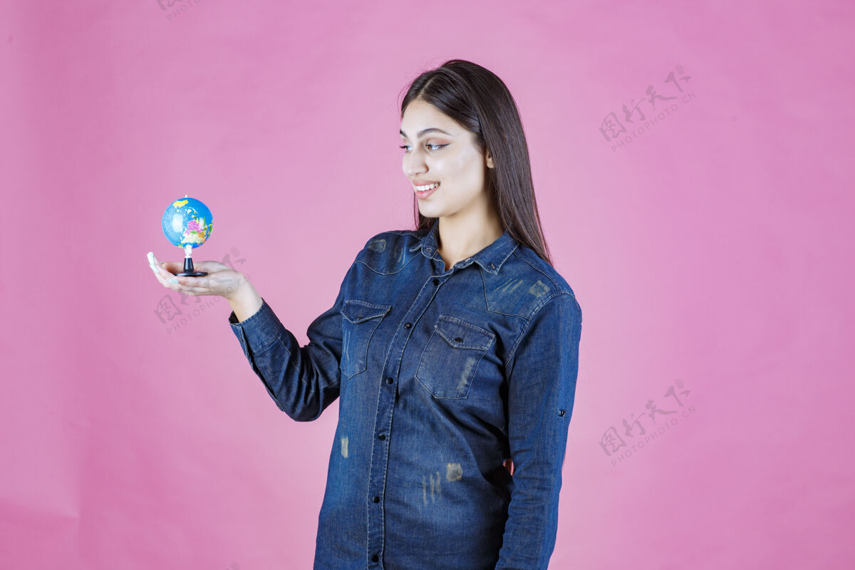教育穿着牛仔夹克的女孩手心里拿着一个迷你地球仪休闲成人装备