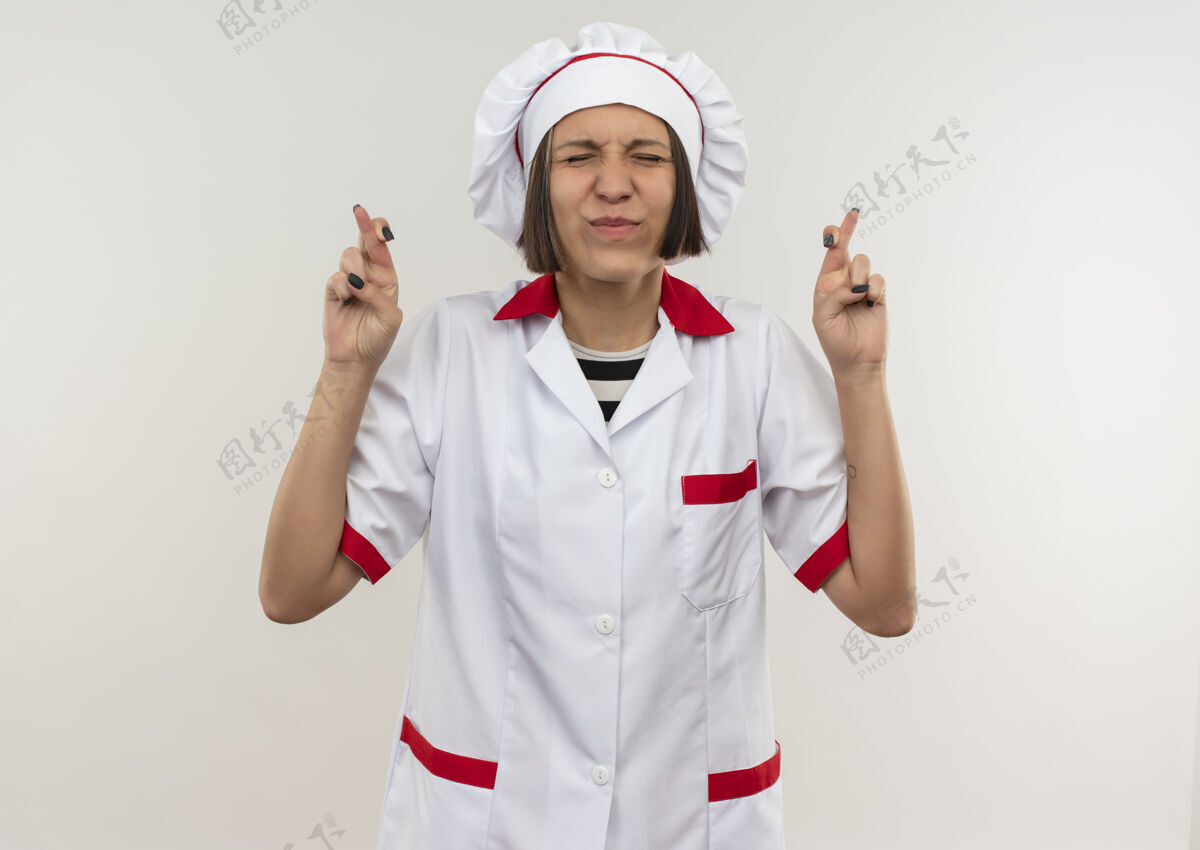 厨师愿年轻的女厨师身着厨师制服 双手交叉 双眼紧闭 背景为白色 留有复印空间年轻愿望手指