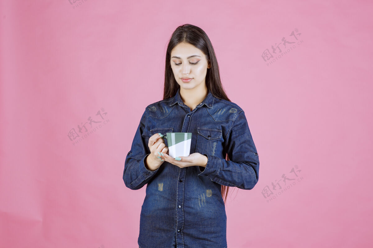 人女孩拿着一个白绿色的咖啡杯 闻着冬天温暖美食