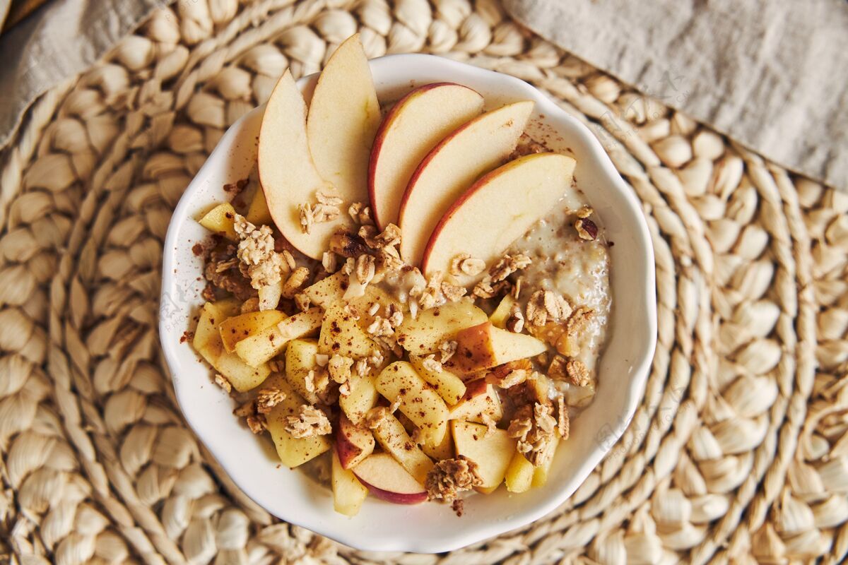 水果高角度拍摄的一碗麦片粥和坚果 以及木桌上的苹果片汤匙零食素食