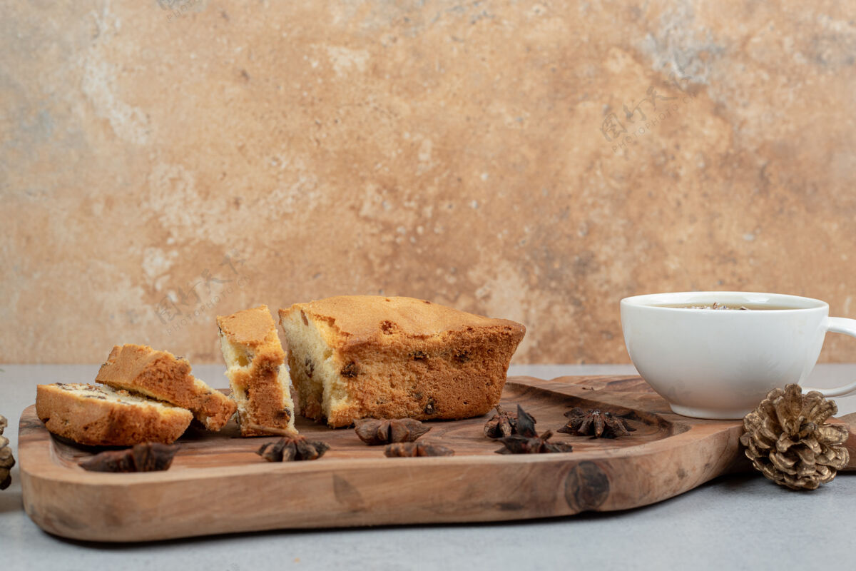 可口美味的松饼加葡萄干和一杯茶放在木板上食物纸杯蛋糕松果