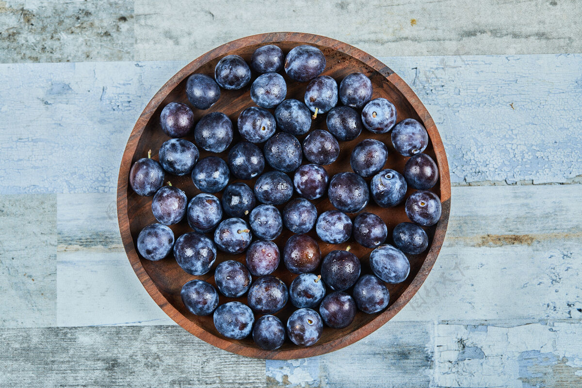 盘子花园李子在一个蓝色的背景板高品质的照片顶部水果成熟