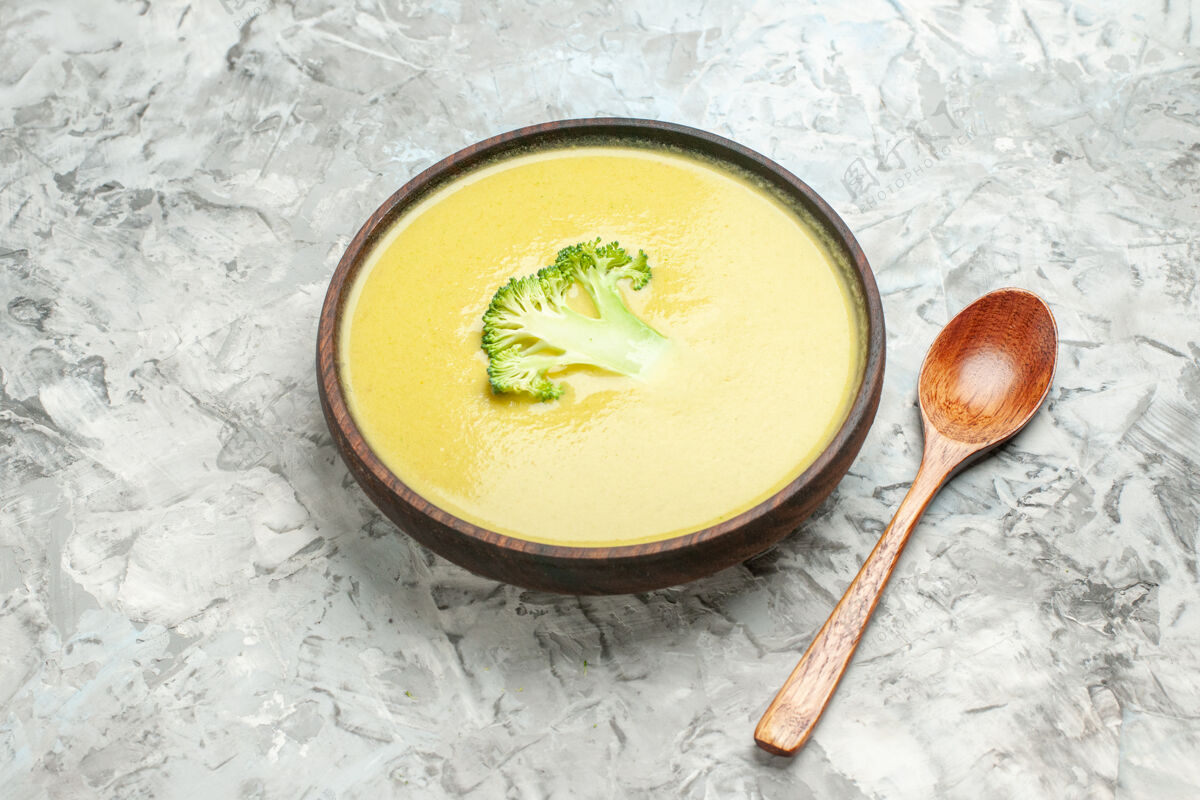餐棕色碗里的奶油西兰花汤和灰色桌子上的勺子的侧视图热的健康碗