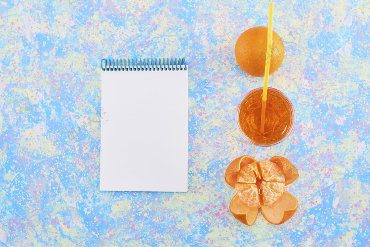 酒吧一杯橘子汁 周围是柑桔 蓝色背景 旁边放一个笔记本高质量的照片餐厅鸡尾酒空白