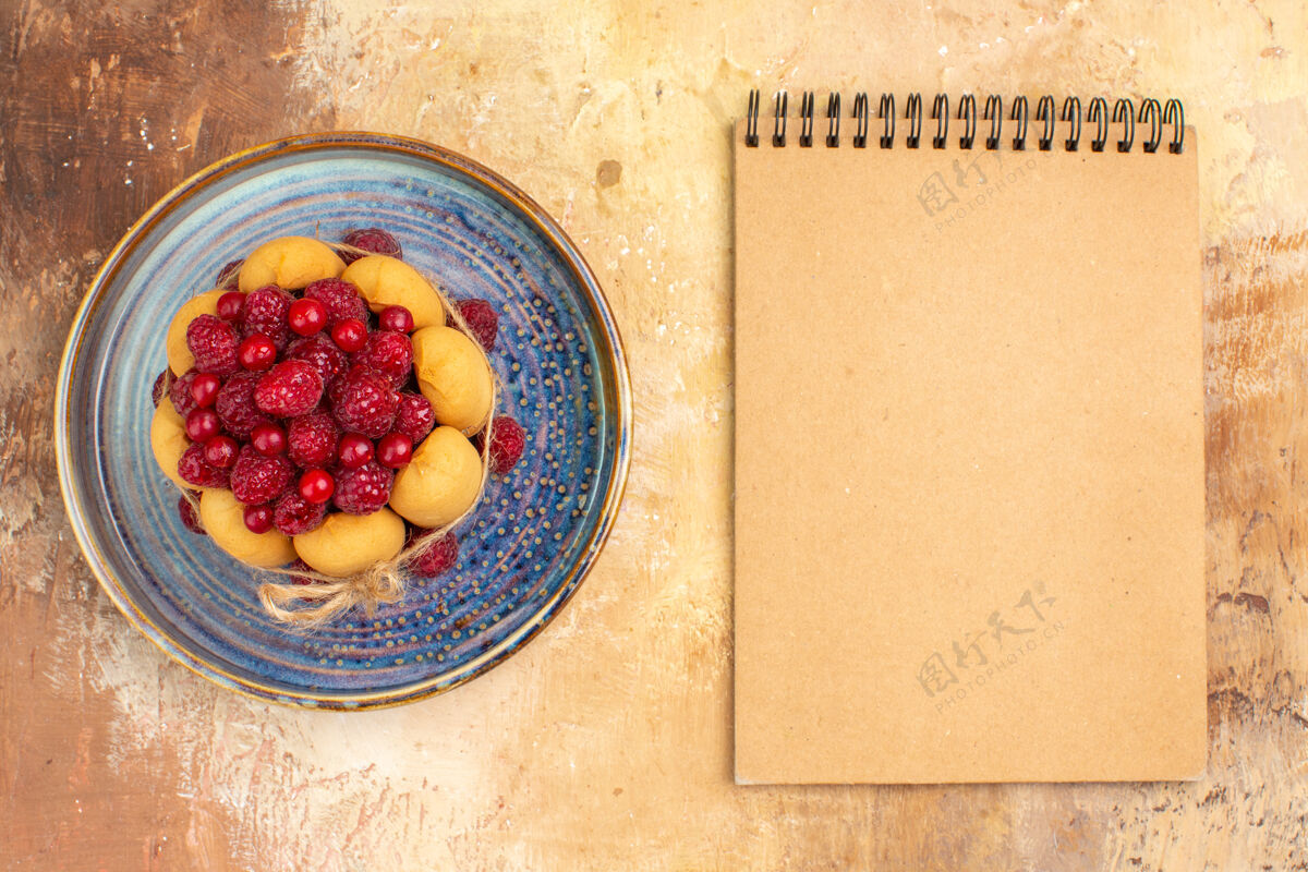 食品新鲜出炉的水果蛋糕和笔记本放在五颜六色的桌子上配料笔记本碗