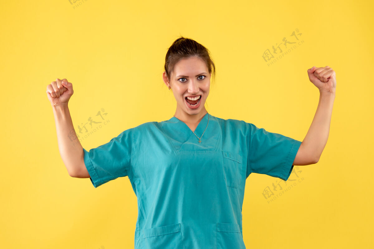 肖像正面图黄色背景上穿着医用衬衫的女医生欢呼雀跃成人正面医疗