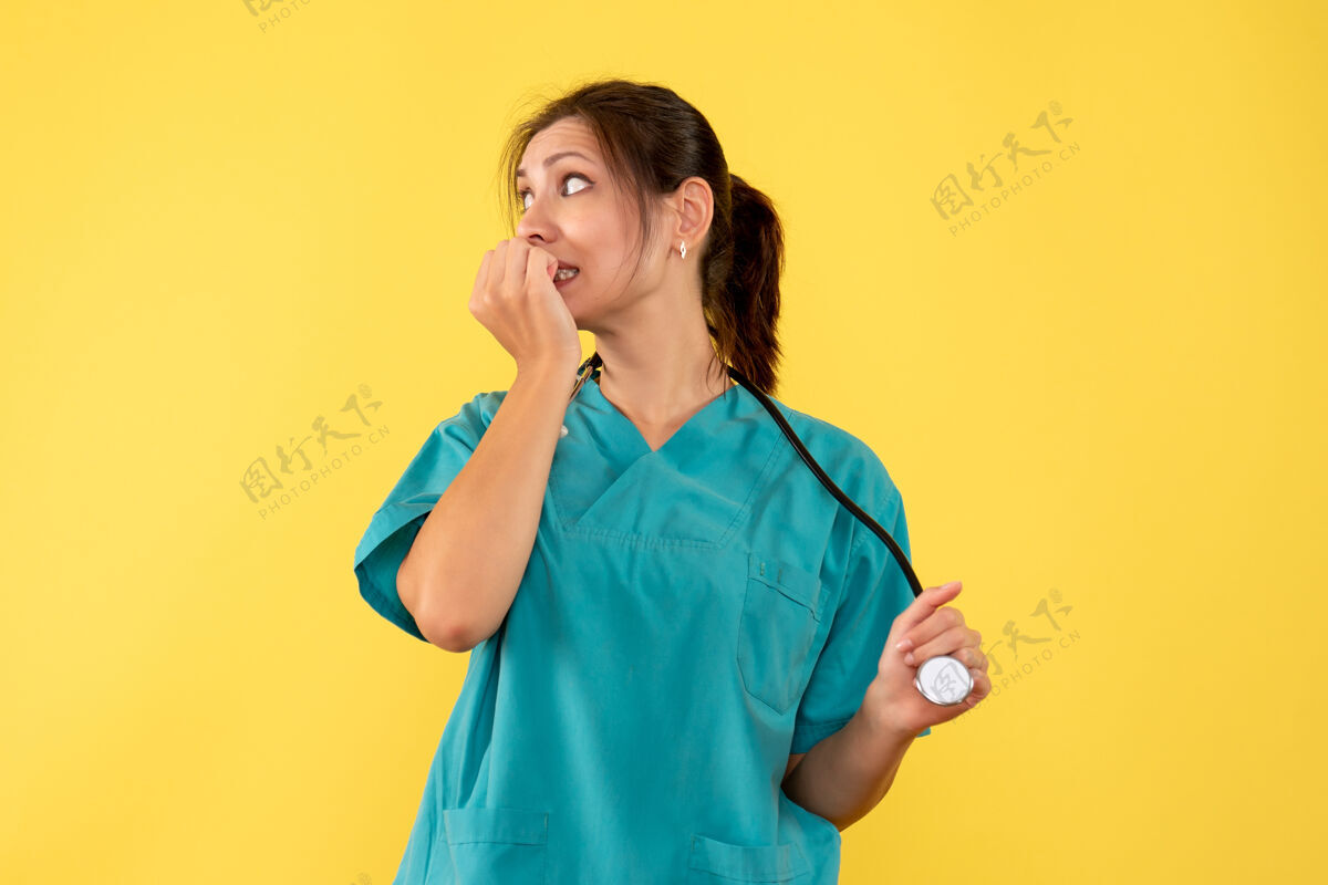 视图正面图黄色背景上穿着医用衬衫的女医生感到紧张医生听诊器女医生