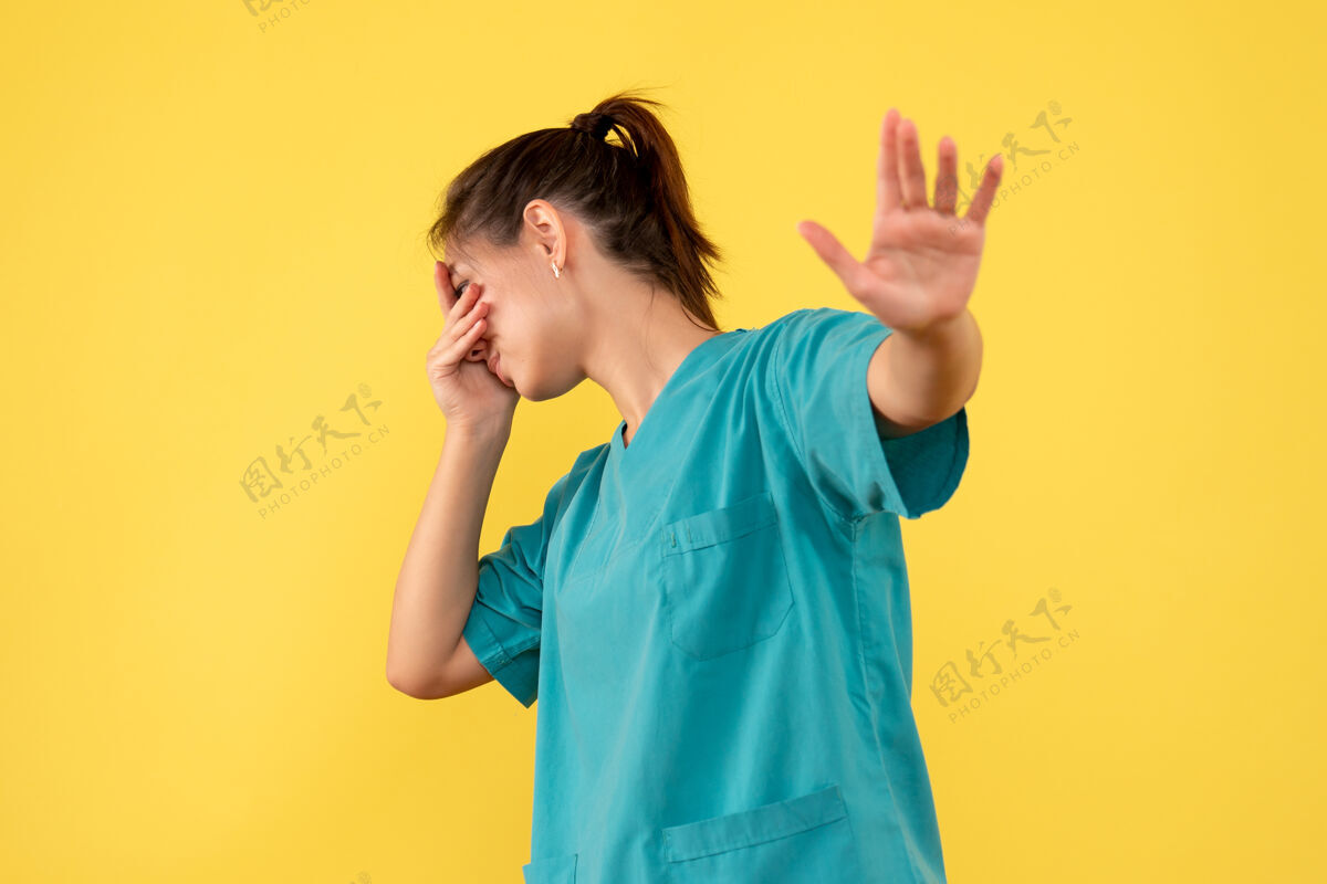 脸正面图黄色背景下 身穿医用衬衫的女医生遮住了她的脸正面病毒健康