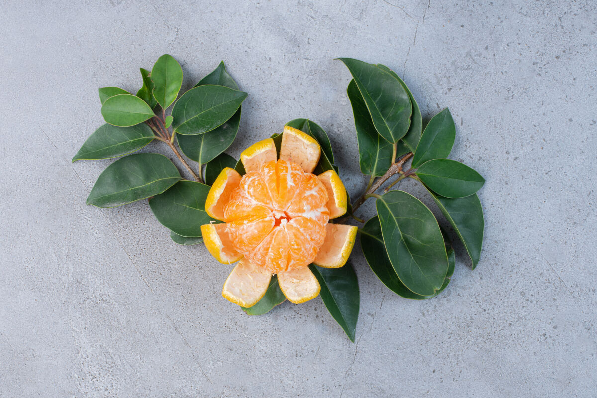 水果剥皮的橘子和大理石背景上的装饰叶橘子饮食美味