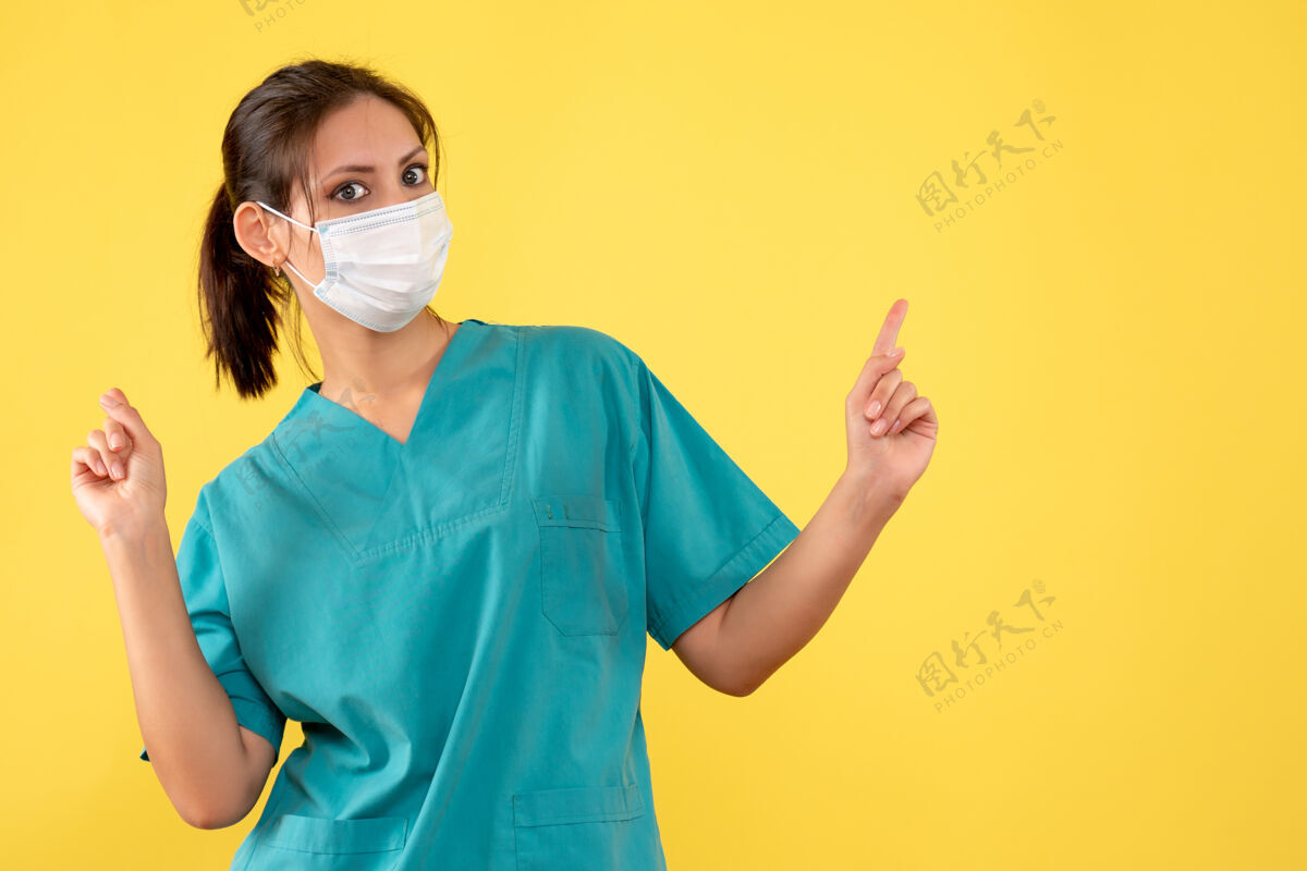 黄色前视图黄色背景上穿着医用衬衫和面罩的女医生正面大流行病毒
