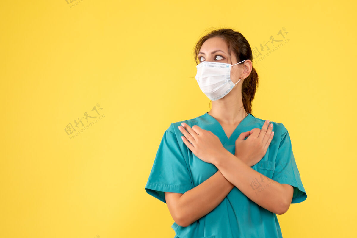 肖像前视图黄色背景上穿着医用衬衫和面罩的女医生面具正面成人