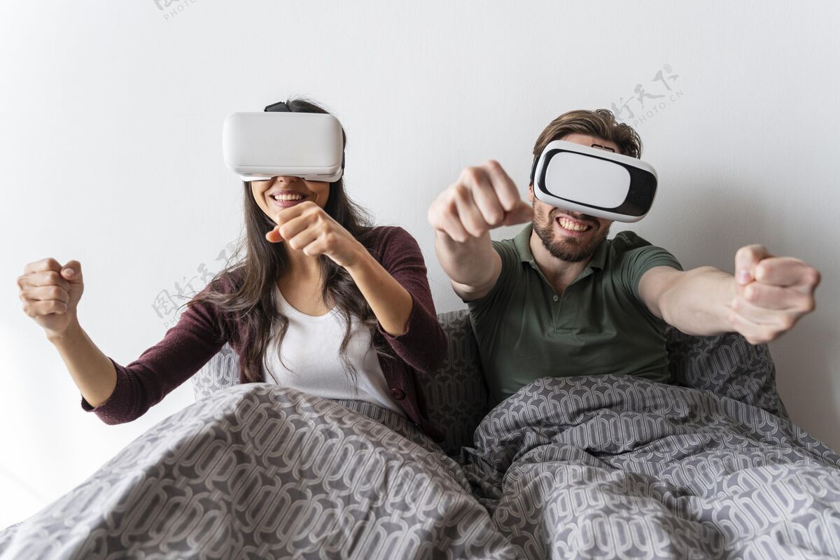 女人笑脸女人和男人在床上使用虚拟现实耳机虚拟现实眼镜水平男人