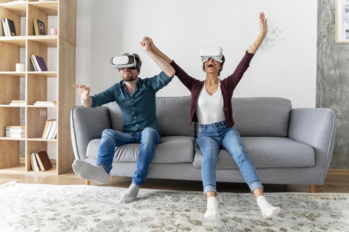 女人男人和女人在家里的沙发上与虚拟现实耳机男人娱乐享受